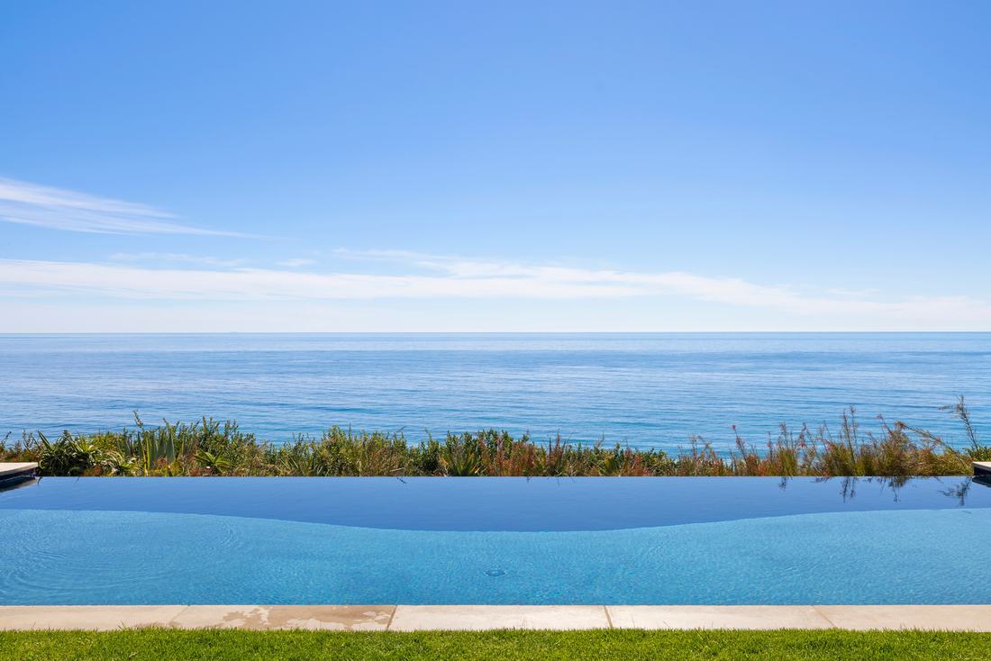 The infinity edge of the pool meeting the Pacific horizon